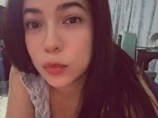 SweetSquiirtxxx has long dark hair and a neutral expression, looking directly at the camera in a close-up shot.