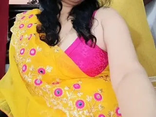Woman in traditional yellow and pink embroidered lehenga choli posing in a bright indoor setting.