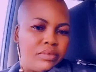 TashabebeX — TashabebeX looks directly into the camera with a neutral expression, showing her shaved head and dark eyes.