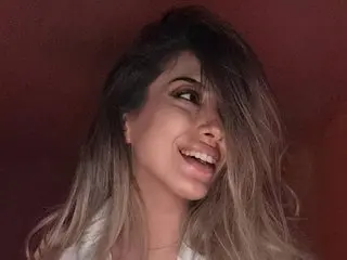 TheaOrre smiles with her long blonde hair partially covering her face in a close-up shot.