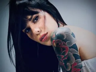 Theinkedgirl poses with her long dark hair, showing off her large, colorful tattoos on her shoulder and arm.