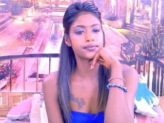 TimTim4u poses with her hand on her chin while wearing a blue top outdoors.