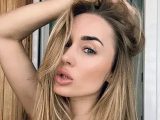 Tina_a poses with her blonde hair swept back, looking directly at the camera with a pouty expression.