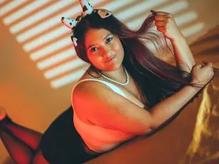 Young woman in white lingerie and dalmatian ears relaxing in warm, sunlit bedroom lighting.