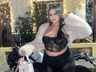 Vanessa_Foxyy poses with long dark hair, wearing a black lace bra and black leggings while wrapped in a white fluffy fur coat.