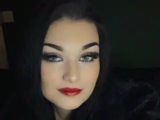 Velvethexx poses close-up, showing her face, dark hair, and eyes with heavy eyelashes and dark eyeliner.