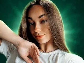 Verba — Verba smiles while running her hand through her long brown hair in a close-up shot.