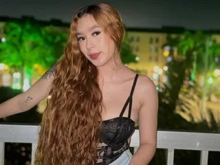 VeronicaDilucas poses with long wavy brown hair wearing a black lace bustier top against a soft-focus night background.