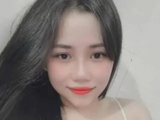 Vicion poses with long black hair and red lipstick, looking directly at the camera against a plain white background.