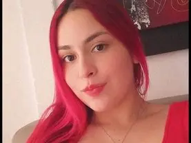 Vickyandsamantha has long red hair and is wearing a red top while looking into the camera.