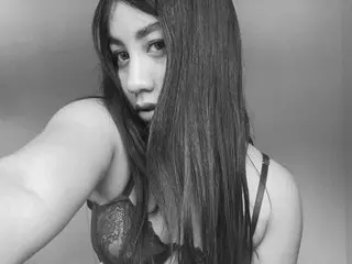 Young woman with long straight hair wearing a lace bralette in a moody black and white indoor portrait.