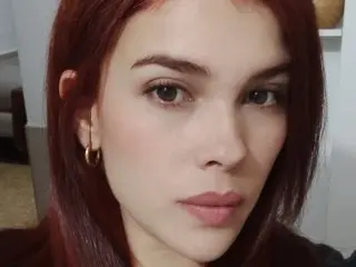 Victoria_Web poses close-up, showing her face and red hair with a direct gaze and a neutral expression.