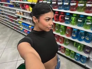 Victoria_broown poses for a selfie in a black crop top while standing in a store aisle filled with colorful mugs.