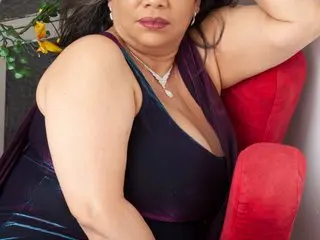 VikyAdams72 poses in a low-cut black velvet top, showing her cleavage and bare shoulders with her dark hair down.