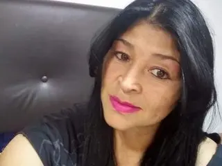 WILDPUSSYCREAMY has long black hair and pink lipstick, posing close-up in a dark setting wearing a black top.