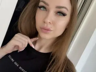 XStormy poses with her long brown hair down, wearing a black t-shirt and looking directly at the camera.