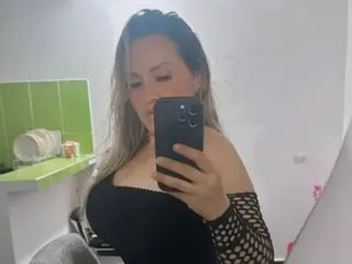Xiomara_Cephei takes a mirror selfie wearing a black off-the-shoulder top and mesh sleeves.