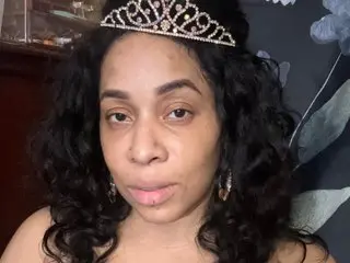 YaBellaKinky looks at the camera with her long, dark curly hair and a sparkling silver tiara on her head.