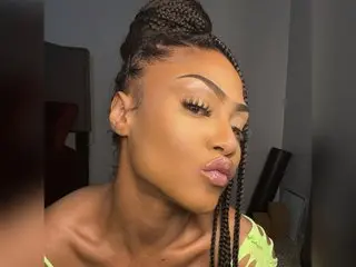 Yiauana poses with her eyes closed, showing her face and long dark braids against a plain background.