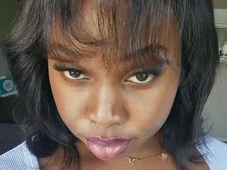 YummyCookiie poses close-up with her dark hair framing her face, looking directly at the camera with a pouty expression.