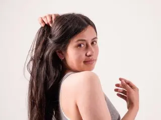ZaidaAlley poses with her long dark hair swept to the side, showing her bare shoulder and back against a plain white background.