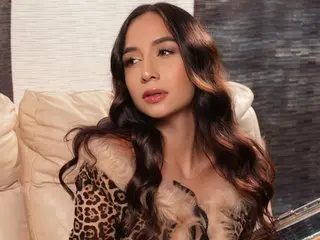 Elegant woman in leopard print outfit sitting on a cream sofa with a glamorous, moody atmosphere.