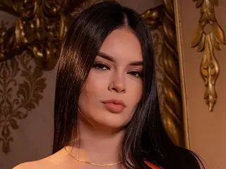 Elegant woman with long dark hair in a gold ornate room wearing a delicate necklace with a sophisticated mood.