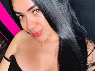 abbiemorgann poses close up, showing her long black hair and cleavage in a black top.