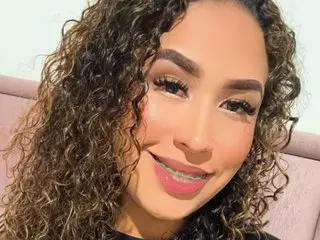 abbyblairs30 smiles with her long, curly brown hair framing her face in a close-up headshot.
