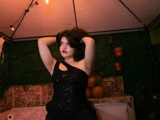 Young woman in a black sequin top posing under warm tent lighting in a moody garden setting.