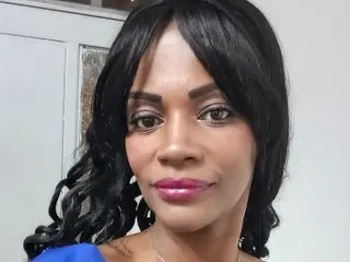 Smiling Black woman with wavy black hair wearing a blue top in a bright indoor setting.
