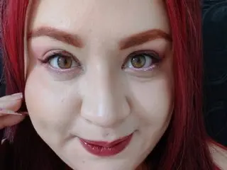 anakeller poses close-up, showing her face, dark red hair, and red lipstick.