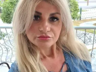 angel40usex has long blonde hair and looks directly at the camera while wearing a blue denim top.