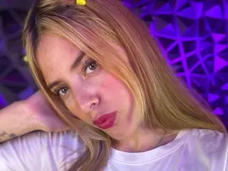 blueviolette poses close-up, looking at the camera with her blonde hair framing her face and wearing a white t-shirt.