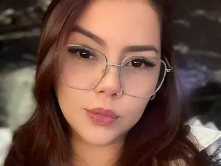 celestina_Bellucci19 looks at the camera with long brown hair and glasses, posing with a neutral expression.