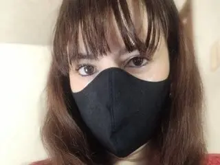 cmisterious shows her face and long brown hair while wearing a black face mask.