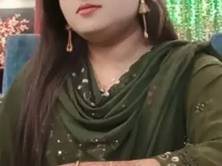 cutebengaligirl1992 wears a dark green traditional outfit and gold earrings while looking at the camera.