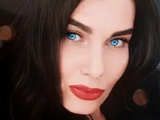 Close-up portrait of a beautiful woman with striking blue eyes and red lipstick looking elegant.