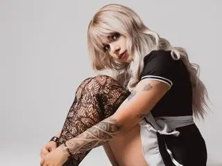 emilyevo poses with her blonde hair down, wearing a black and white top while showing off her bare legs and arms.