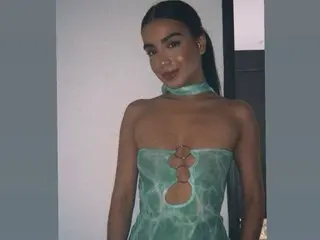 emmaelliss poses in a light green strapless top that features a cutout exposing her chest and cleavage, looking directly at the camera with long dark hair.