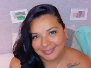 fatnaughtyass smiles with her long dark hair down, showing her bare shoulders and chest in a close-up shot.
