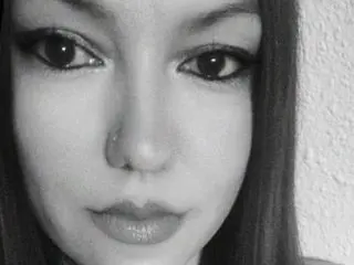 gabriellelust looks directly at the camera with a close-up headshot, showing her eyes, nose, and lips against a plain background.