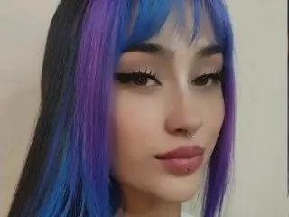 hil_tatta has long, straight purple and blue hair and a nose ring, looking directly at the camera.