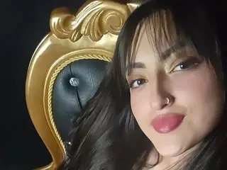 hilary_thompson poses for a close-up selfie, showing her face, dark hair, and pink lipstick against a dark background.