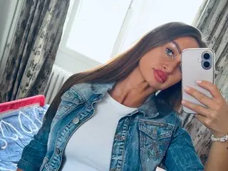 jessicahampton91 poses for a selfie wearing a white top and denim jacket, showing her long brown hair and red lipstick.