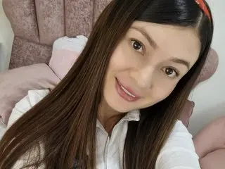 katecolins smiling in a white shirt with her long brown hair down in a bedroom setting.