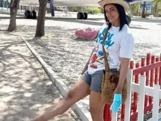 kateleyagray poses outdoors in a white t-shirt and grey shorts, showing her long legs and dark hair while wearing a wide-brimmed hat.