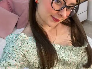 khalifafletcher poses with long brown hair and glasses, wearing a light green floral print top while looking at the camera.