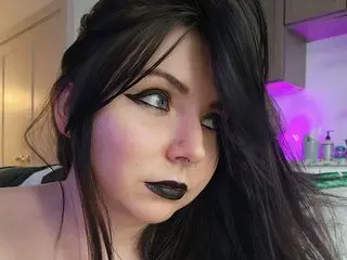 kimbrrrrly poses with long black hair and heavy black eyeliner, looking directly at the camera with a serious expression.