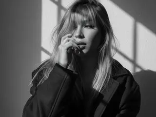 lanna_lee poses with her hand near her mouth, showing her long hair and face in a black and white close-up shot.